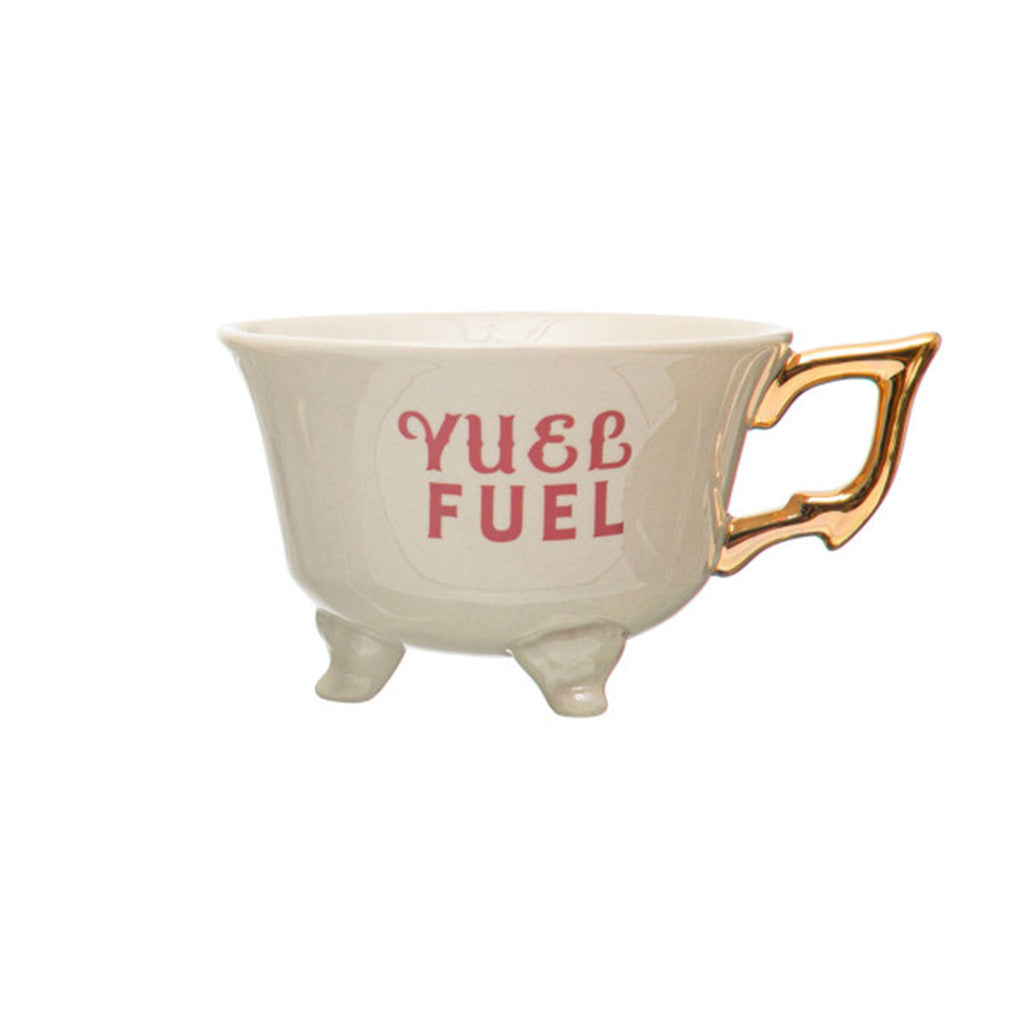 Creative Co-op stoneware footed teacup with "yuel fuel" in playful red lettering and gold electroplated handle on the right.