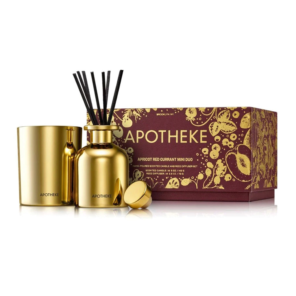 Apotheke Apricot Red Currant Scented Mini Duo limited edition holiday gift set with a mini candle and reed diffuser, both in shiny gold glass vessels. Packaged in a maroon gift box with gold foil fruit illustrations.