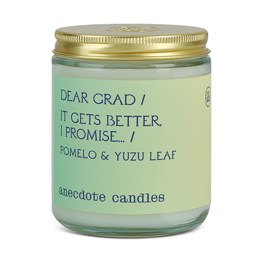 anecdote candle in clear glass jar with gold lid and green to yellow ombre label with "dear grad / it gets better, i promise" in blue lettering along with "pomelo & yuzu leaf"