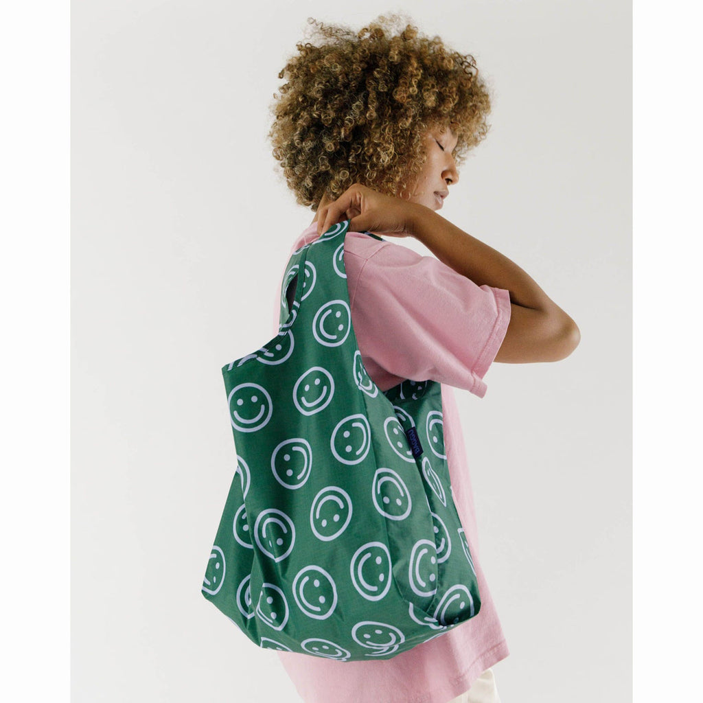 baggu standard size ripstop nylon reusable bag in forest green happy pattern on shoulder