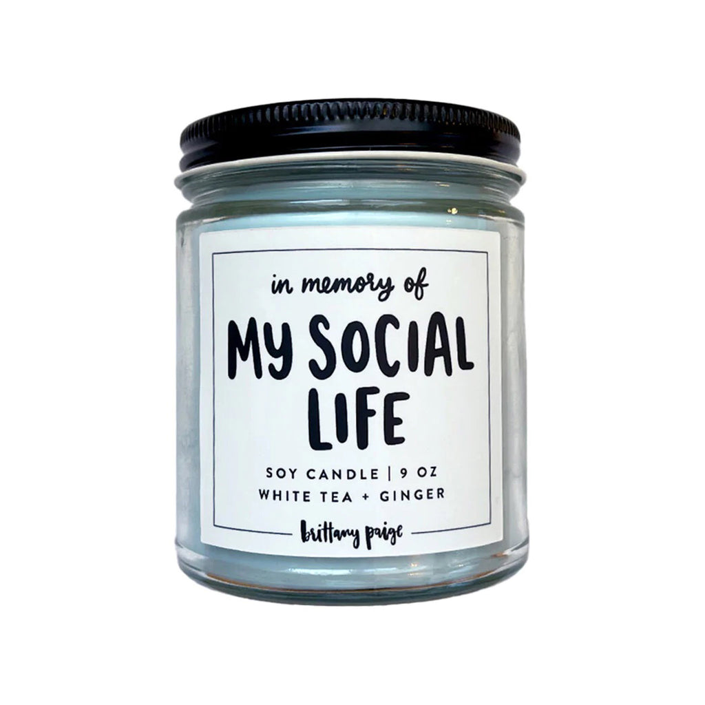 In Memory of My Social Life white tea and ginger scented light blue soy wax candle in a clear glass jar with black screw-on lid.