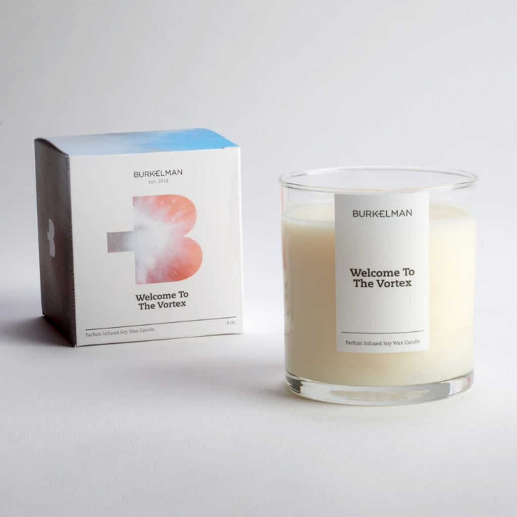 burkelman welcome to the vortex scented soy wax candle in clear glass tumbler with white label and white box front with a cut out B with a light vortex in it