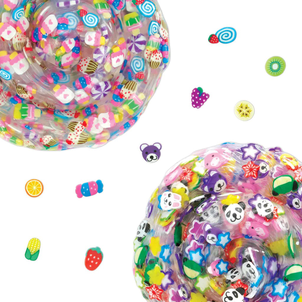 two blobs of clear slime with different colorful clay pieces mixed in. Little clay ear of corn, orange, strawberry, candy piece, bear, grapes, slice of banana and slice of kiwi are shown in between the 2 blobs.