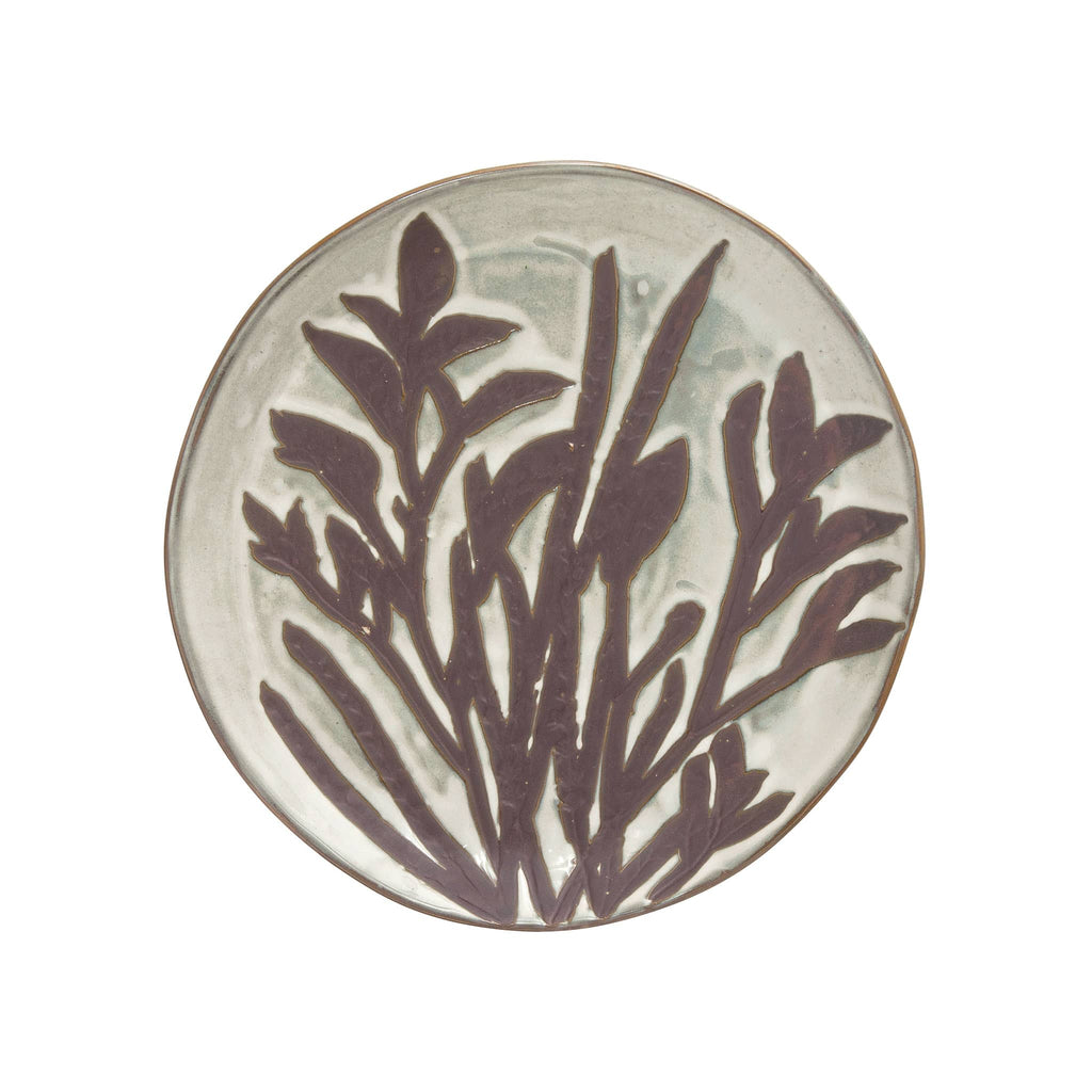 Round hand-painted debossed stoneware plate with cream color reactive glaze and an image of stems and flowers in wax relief.