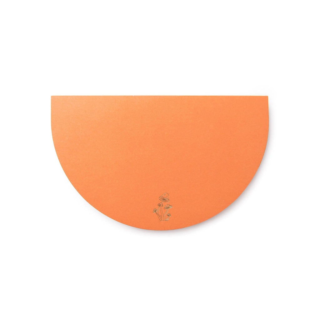 Half-moon shaped notepad with tiny gold mushroom illustration on orange paper.