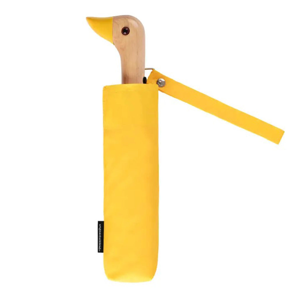 Original Duckhead compact, eco-friendly, wind resistant umbrella in bright yellow, folded into matching sleeve with duck head wood handle peeking out the top.