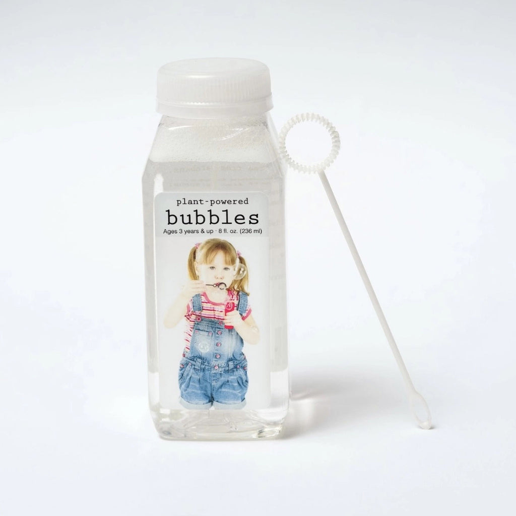 eco-kids plant-powered bubble solution in clear bottle with white wand and photo of a girl wearing overalls blowing bubbles on the front