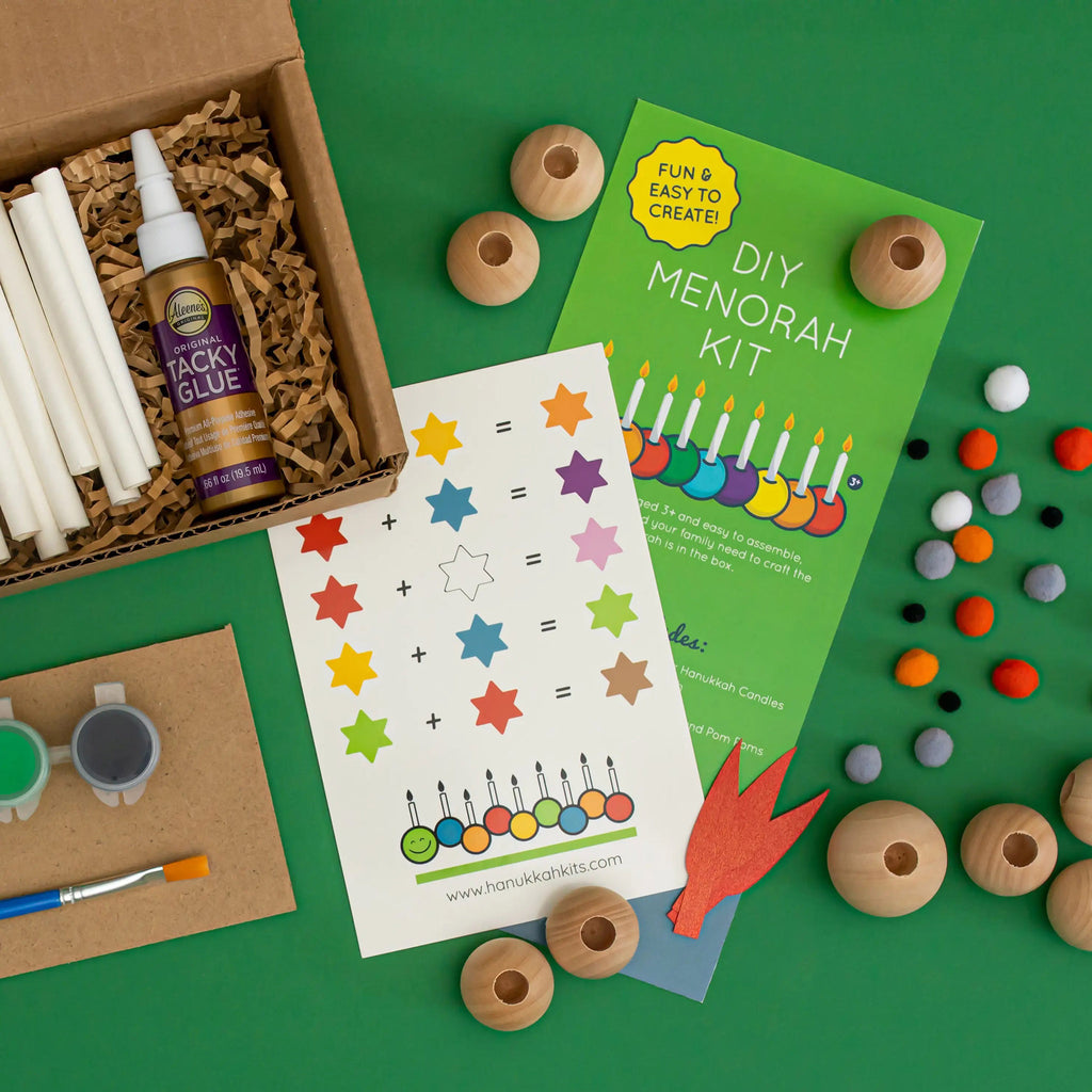DIY caterpillar menorah kit for kids, contents spread out on a green background.