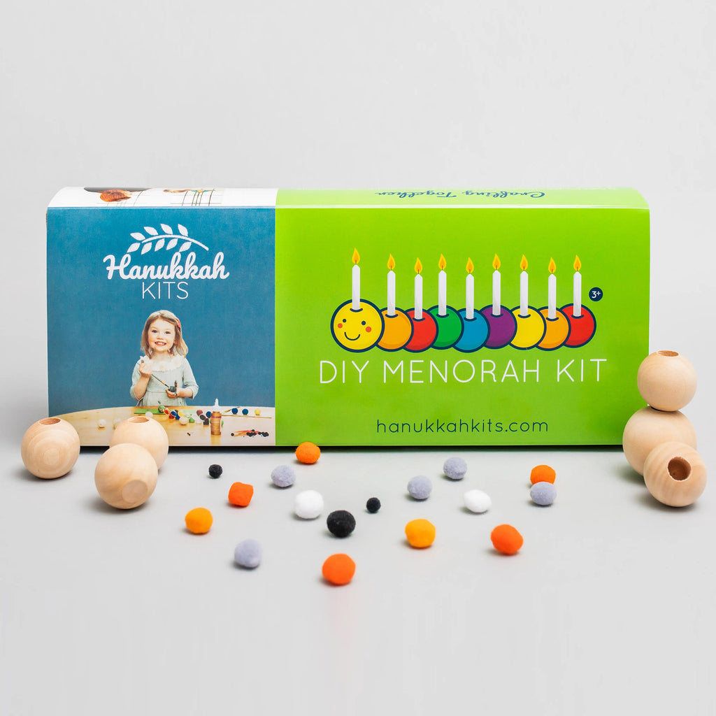 DIY caterpillar menorah kit for kids, box packaging with wood balls and pompoms in front on a gray background.
