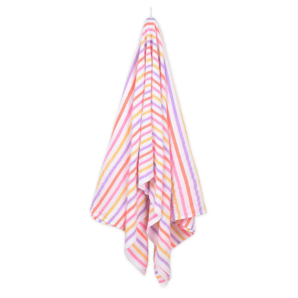 Las Bayadas La Gaby pink, orange, purple and yellow striped woven cotton blend beach blanket towel, hanging from a white peg.