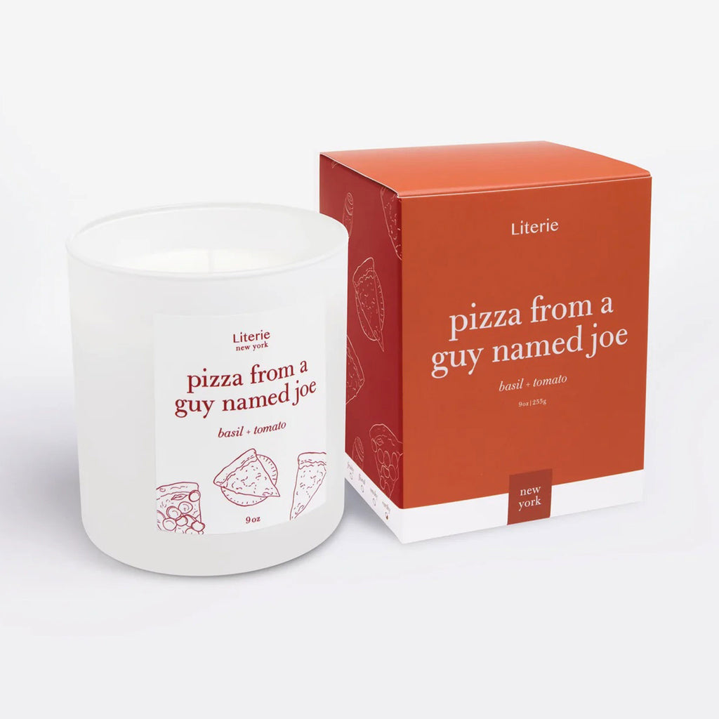 "Pizza From a Guy Named Joe" basil and tomato scented candle by Literie in a white matte glass tumbler with name of candle and pizza slice illustrations in red and matching red gift box with pizza slice illustrations in white on the side.