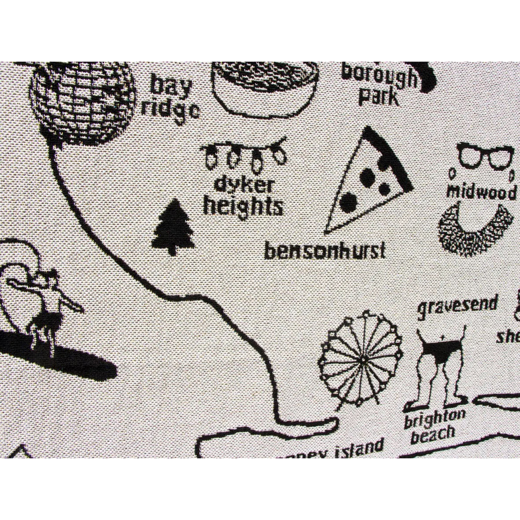 Detail of Dyker, Heights, Bay Ridge and Bensonhurst on a Brooklyn-themed knit throw blanket, illustrations and wording in black on a white backdrop.