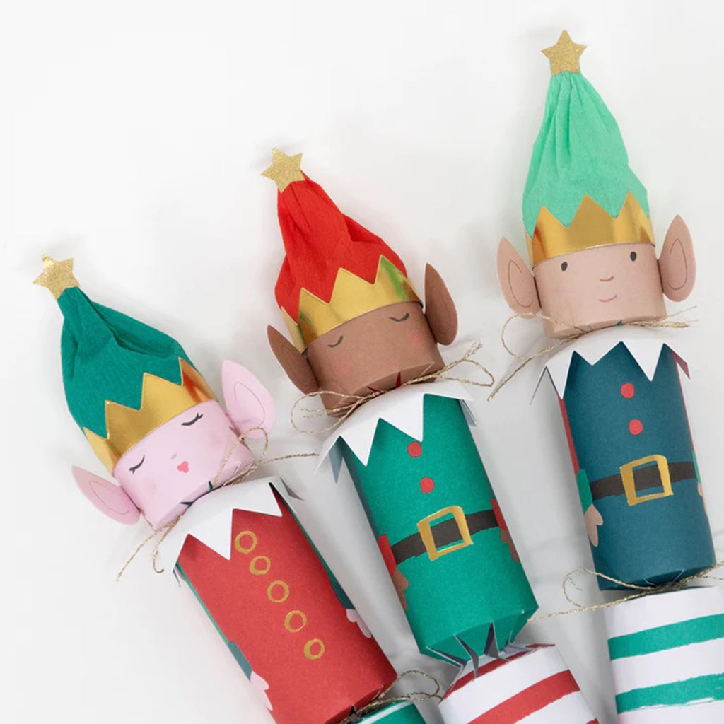 3 elf party crackers dressed in red, green, white and gold outfits with striped bottoms and gold glitter stars on the top of their hats.