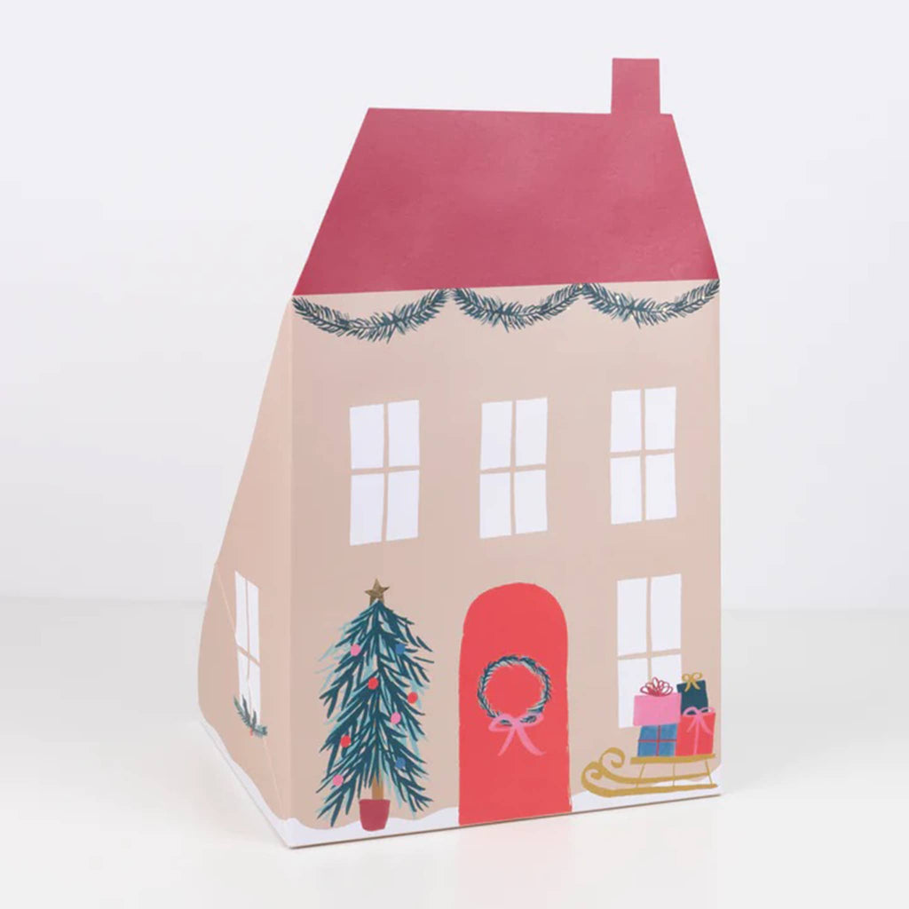 Back of the Meri Meri Santa's house pop up advent calendar of a tan house with red roof and red door with wreath, sides extended to stand on its own.