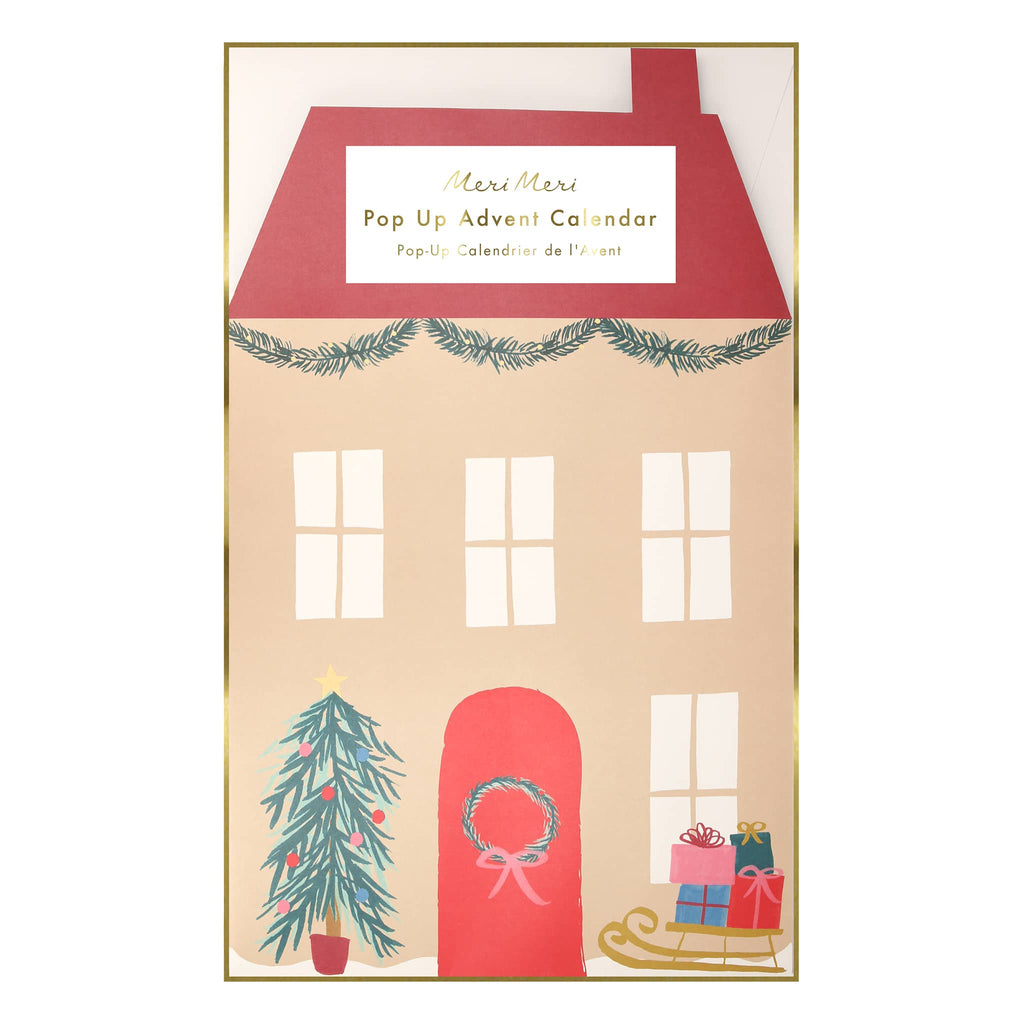 Meri Meri Santa's house pop up advent calendar in flat packaging that shows the front of a tan house with red roof and red door with wreath.