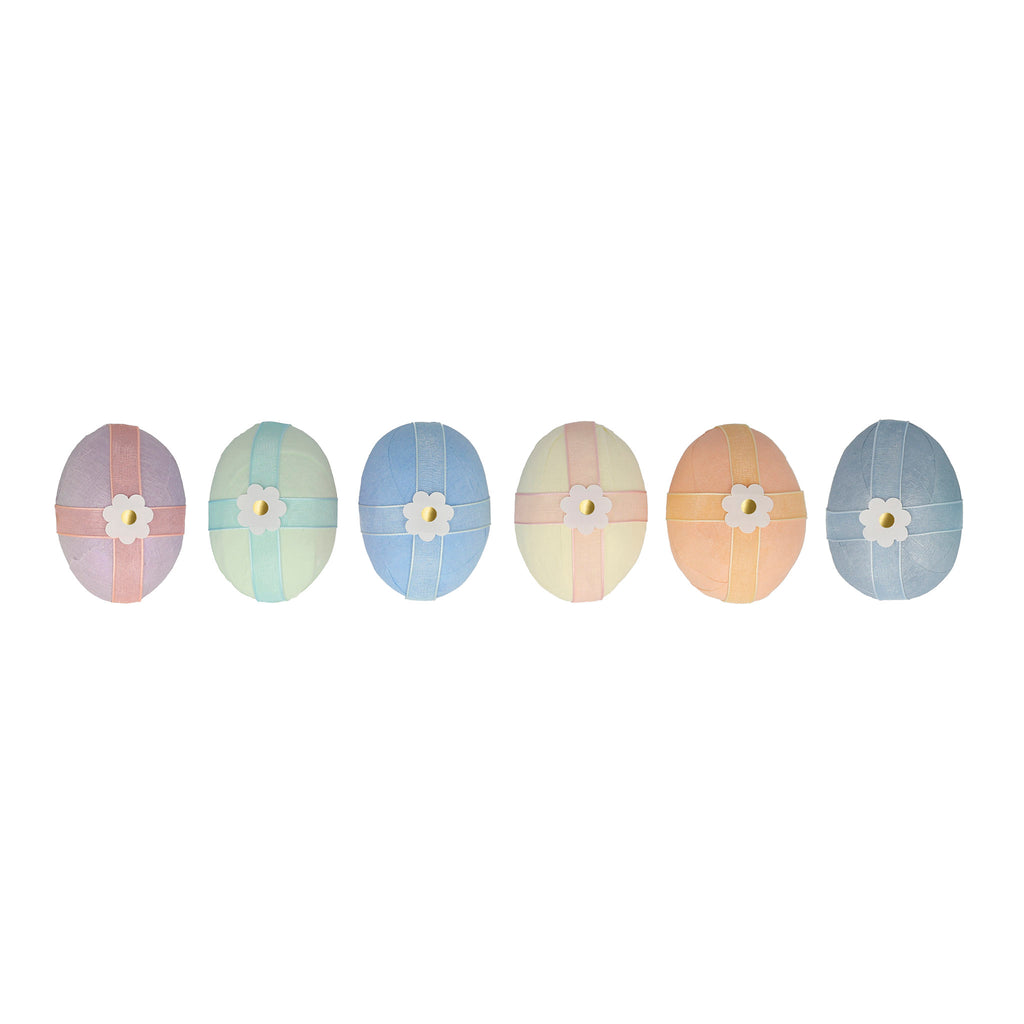 Meri Meri crepe paper wrapped surprise eggs lined up in a row, each in a different color paper with organza ribbon and daisy sticker.
