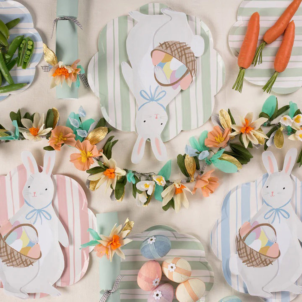 A Meri Meri Easter table setting with Bunny with Basket Plates, Ticking Stripe Dinner Plates, Spring Posy Garland, Floral Party Crackers and Surprise Eggs.