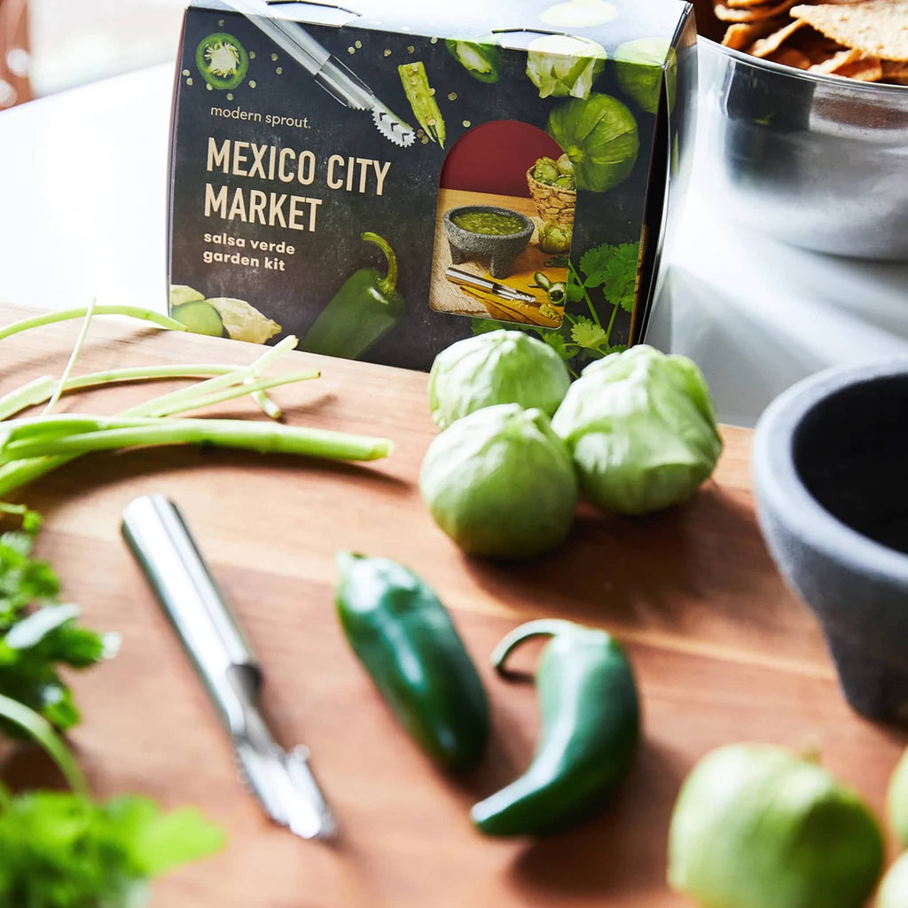 Black box packaging for the Mexico City Market Salsa Verde Garden Kit in the background with tomatillos, jalapenos and cilantro on a cutting board in front.