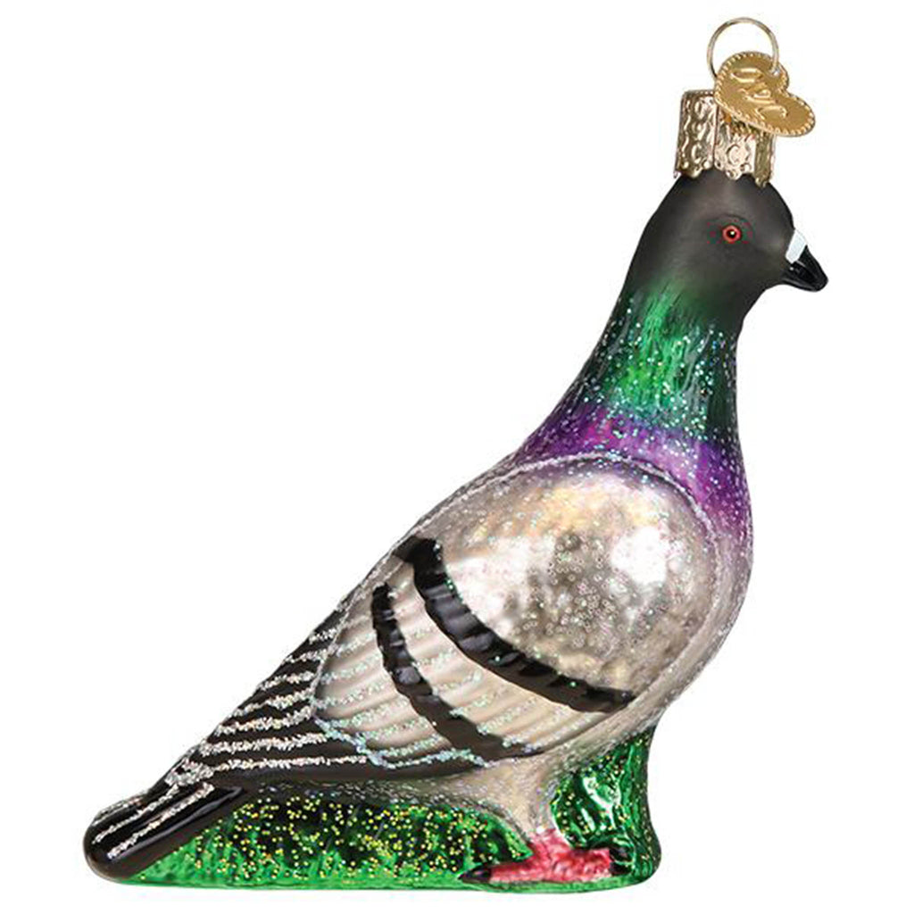Left side view of a glass holiday ornament that looks like a glittery pigeon standing in grass.