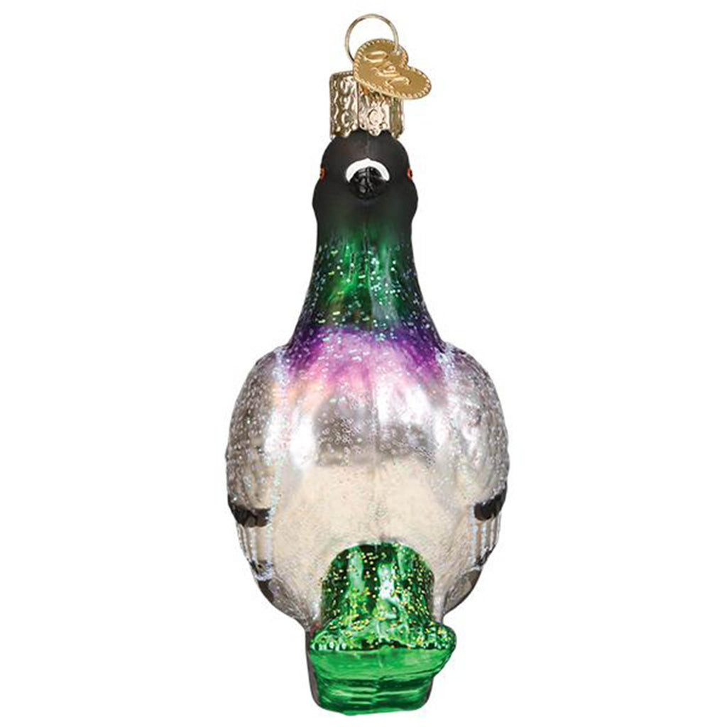 Front view of a glass holiday ornament that looks like a glittery pigeon standing in grass.