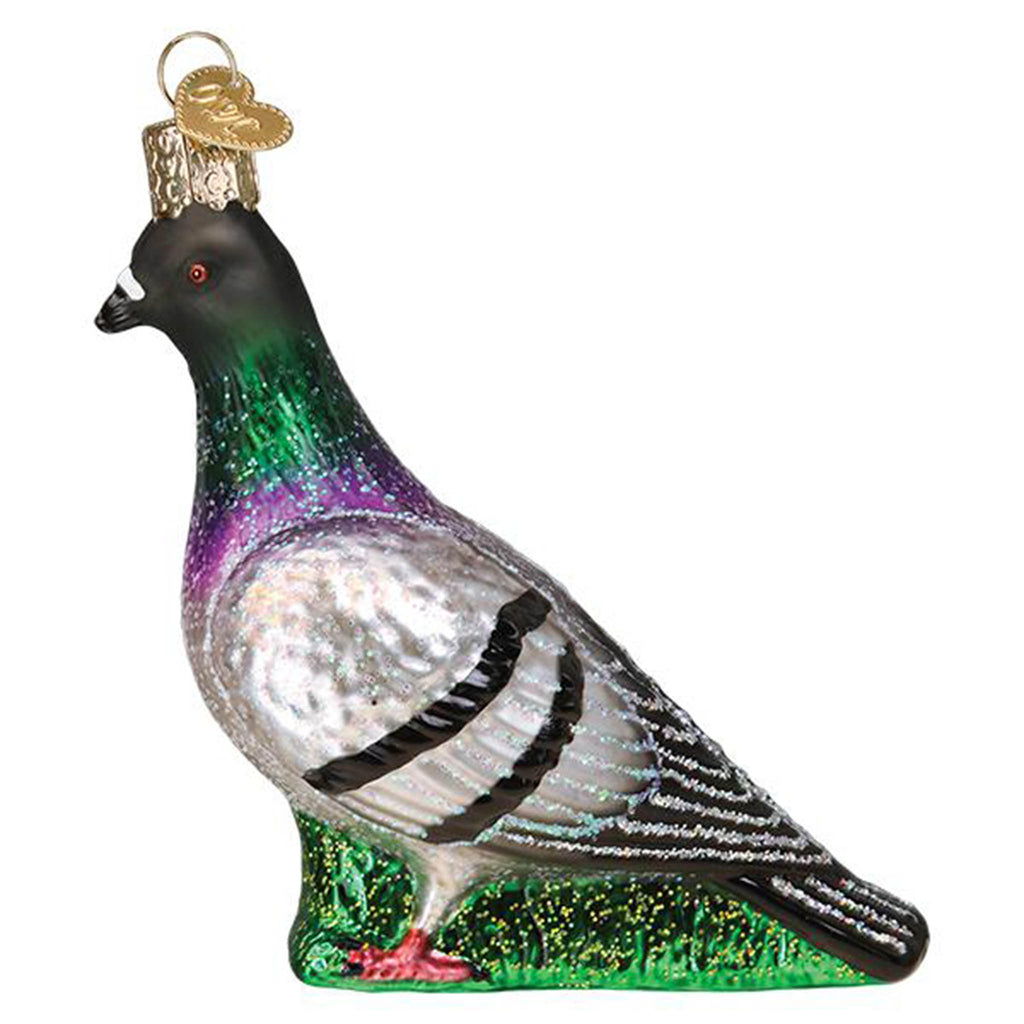 Right side view of a glass holiday ornament that looks like a glittery pigeon standing in grass.