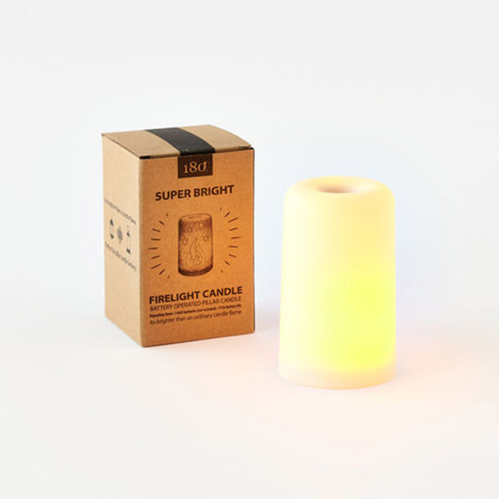Super bright battery operated flameless pillar candle lit up with kraft paper box packaging in background.