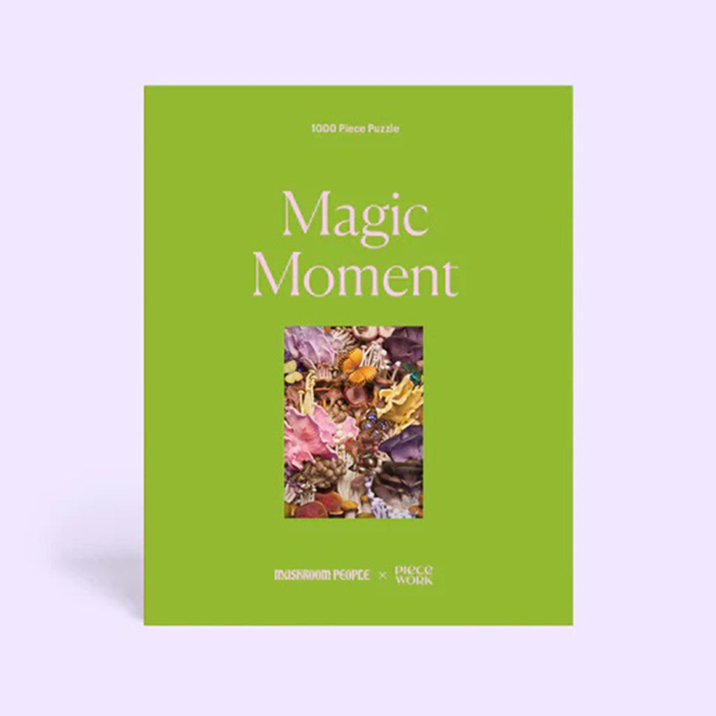 Magic Moment 1000 piece puzzle in moss green box with puzzle image on the front, sitting on a light purple background, front view.