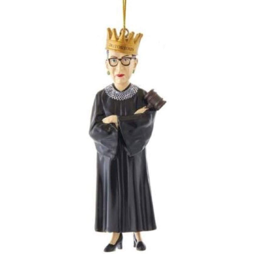 resin ornament of ruth bader ginsburg standing in a lace collar and robe, holding a gavel, and wearing a crown with the word notorious
