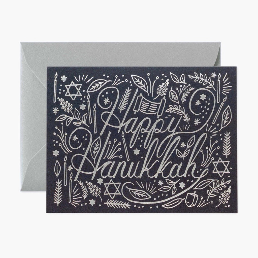 Navy blue card with "Happy Hanukkah" in metallic silver foil along with leaves, candles, the torah, dreidel and star of david. Comes with a matching metallic silver envelope.