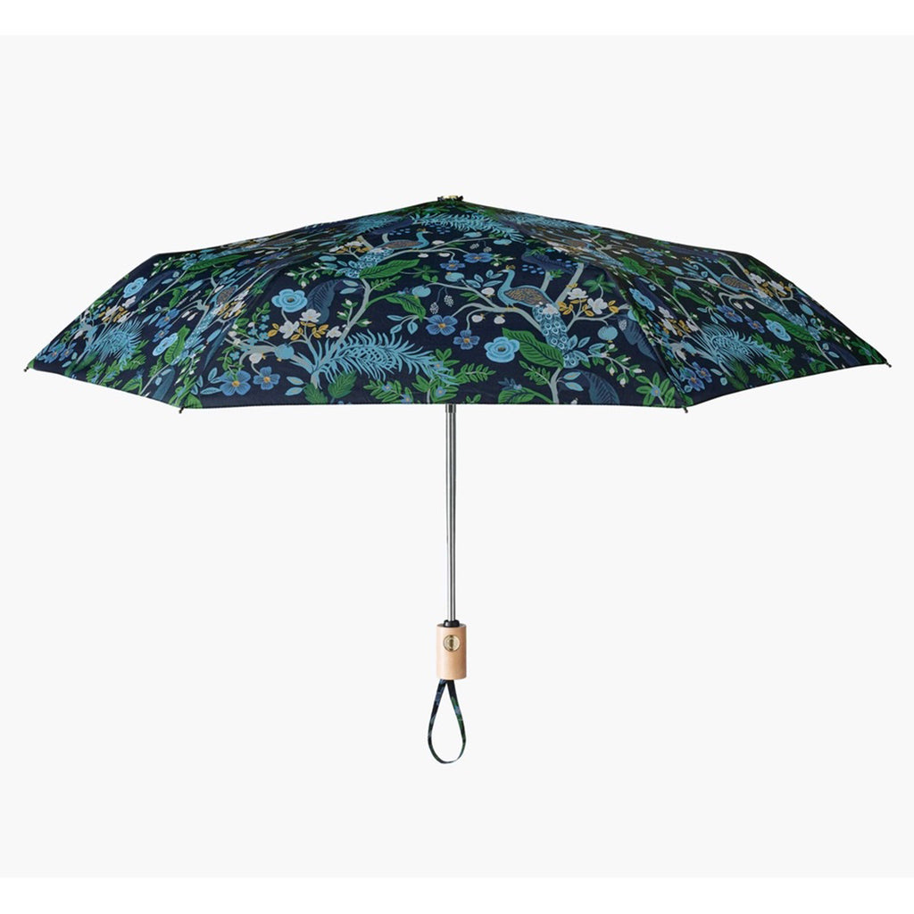 rifle paper company midnight blue umbrella with peacocks perched on winding floral branches, open, side view.