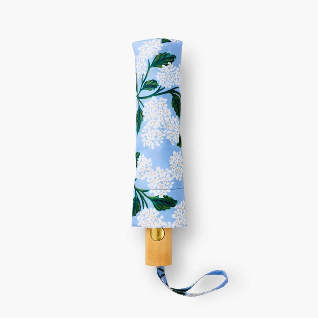 rifle paper company light blue umbrella with white hydrangeas and green leaves folded and in matching sleeve