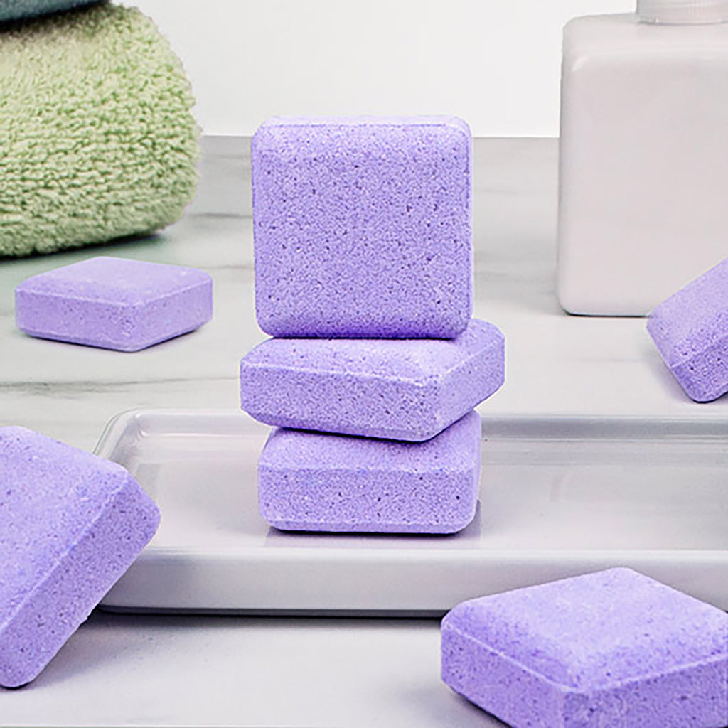 gift republic 7 purple shower steamer tablets on white ceramic dish and white marble surface with a green towel in corner