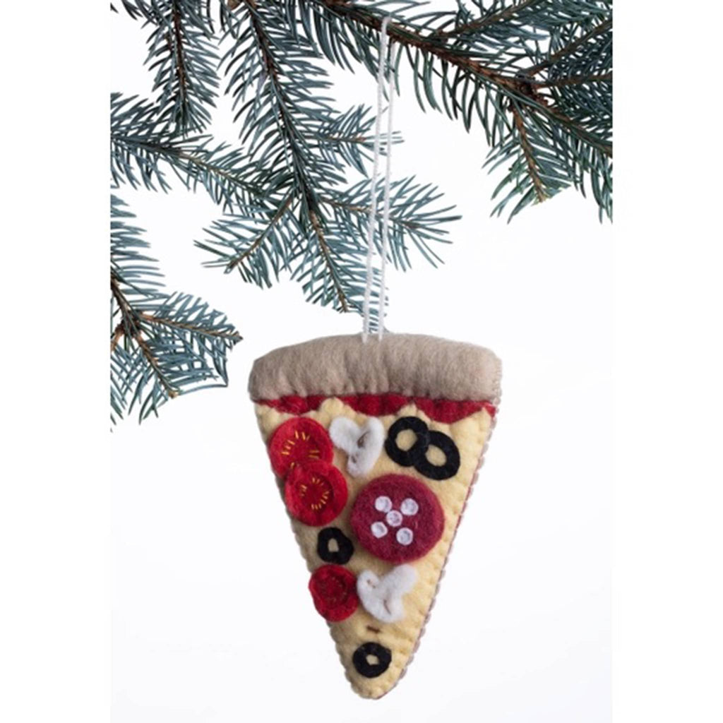 Front view of felt holiday ornament that looks like a slice of pizza with tomatoes, black olives, mushrooms and pepperoni, hanging from an evergreen tree branch.