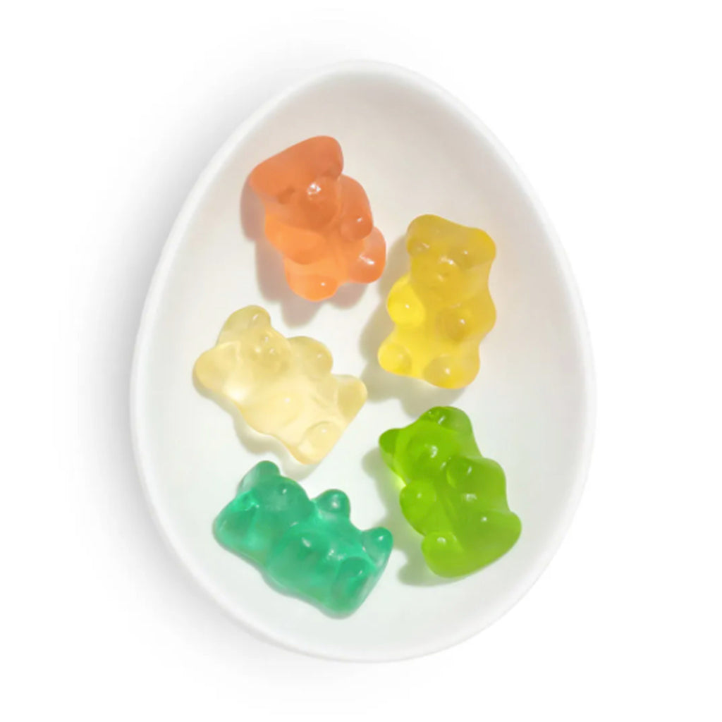 sugarfina fruit flavored rainbow bear gummy candy in yellow, green, orange, and light yellow in white oval dish
