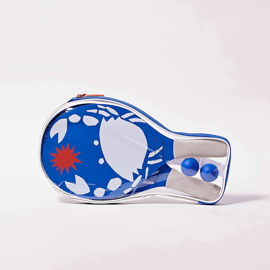 sunnylife 2 beach bats in whack print with white foam handles and blue paddles with a white crab and red sun along with 2 blue balls in clear plastic case packaging