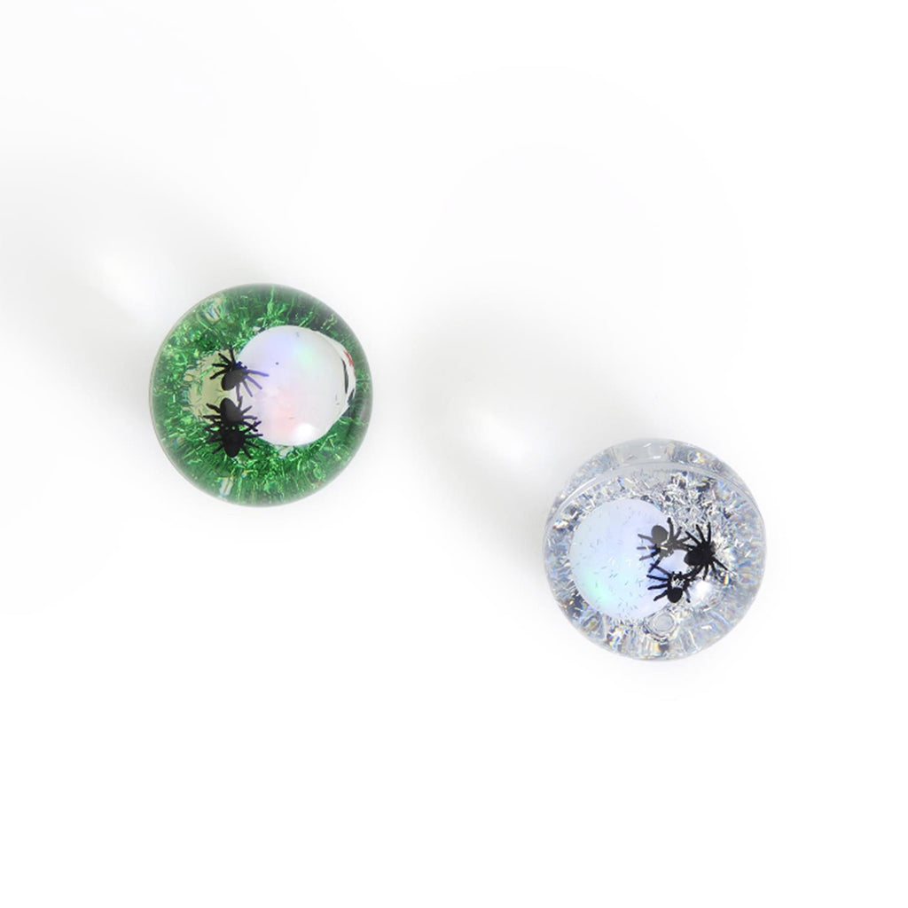 Top view of rubber bouncing balls with a skull, little black spiders and green or silver glitter.