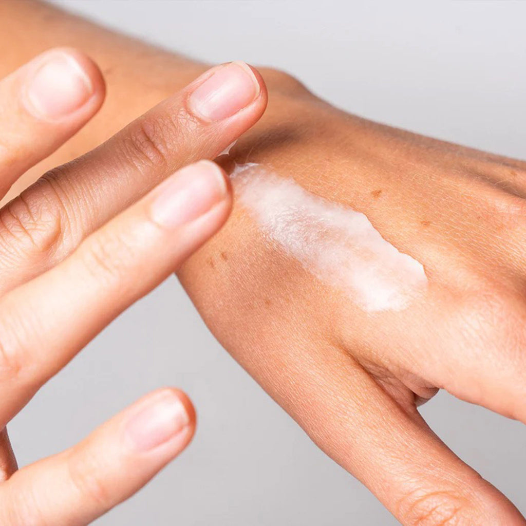 Forest alchemy eye cream being smeared on the back of a hand with a finger to show texture.