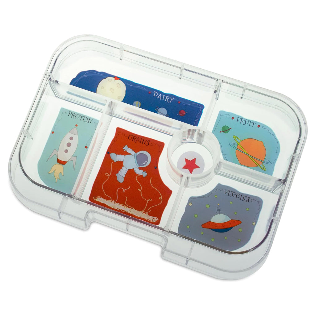 Yumbox lunch box clear tray insert divided into 6 compartments. Each compartment has an illustration (planets, moon, earth, astronaut, spaceship, red star and rocket) and the 5 larger compartments each have a label of dairy, protein, grains, fruit or veggies in light blue or dark blue script letters.